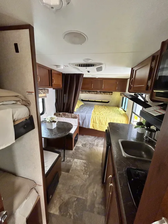 Inside an RV rental: a compact yet complete living space with bunk beds, a kitchen, and a main bedroom.. Jayco Jay Flight SLX 2017