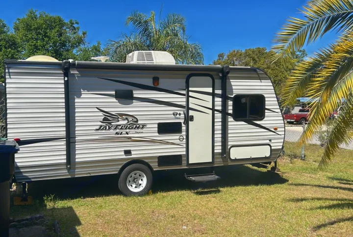 This white and gray Jay Flight SLX travel trailer, parked in a sunny yard, is ready for your next RV rental adventure.. Jayco Jay Flight SLX 2017