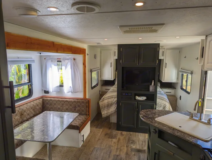 A spacious rv rental interior showing a dinette, kitchen with sink, and bedroom with a TV unit, ideal for travel.. Keystone RV Springdale Eco-Lite 2016