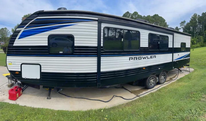 Spacious Prowler RV rental parked outdoors. This white and black travel trailer has blue accents.. Heartland RVs Prowler 2022
