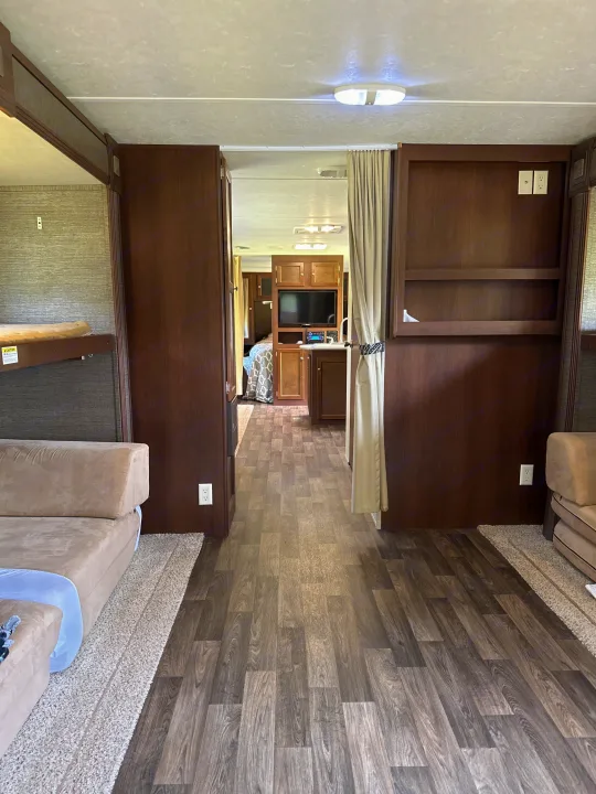 Inside a modern RV rental: a comfortable living area with bunk beds, sofa, and a clear path to the rear section.. Keystone RV Bullet Ultra Lite 2015