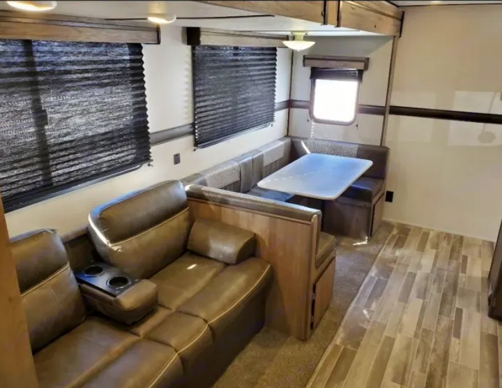 Explore this RV rental's inviting interior: a brown sectional sofa with recliners and a cozy U-shaped dinette area.. Crossroads RV Zinger 2020