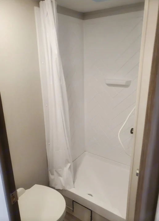 RV rental's compact bathroom: includes a toilet and a clean white shower with patterned walls.. Crossroads RV Zinger 2020
