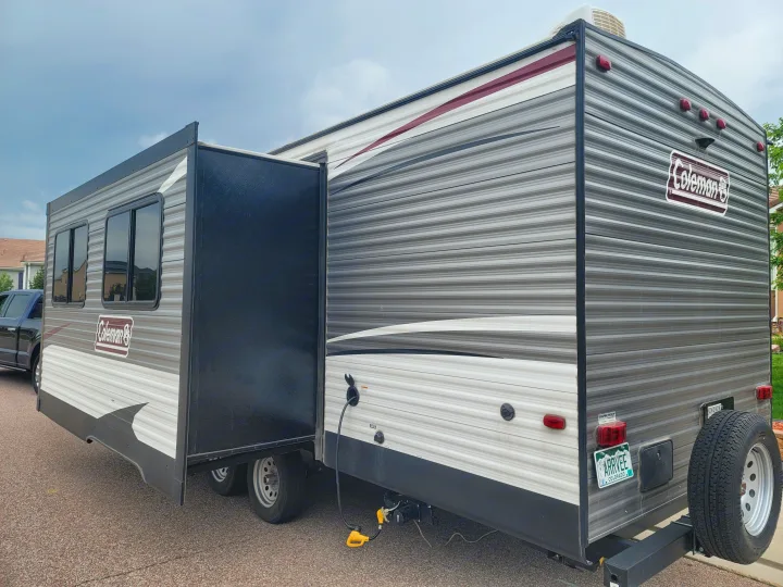 Coleman RV rental: A striped gray travel trailer with its slide-out extended and power connected, ready for your next adventure.. Dutchmen Coleman Lantern 2019
