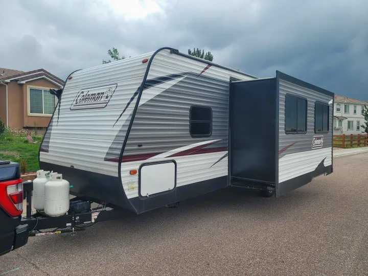 This Coleman travel trailer, with its side extended, is ready for your next RV rental adventure on a cloudy day.. Dutchmen Coleman Lantern 2019