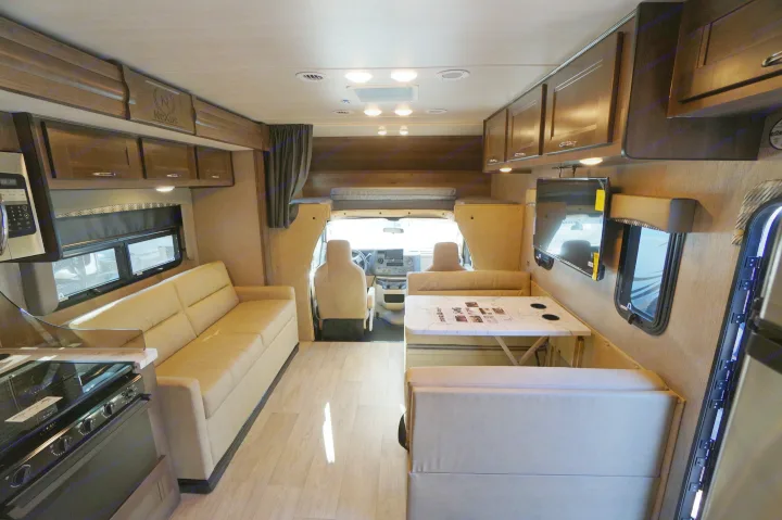 Spacious RV rental interior with dinette, sofa, kitchen, and driver's cabin, offering a complete living space for travel.. Nexus Triumph 32T 2023