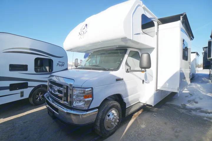 A bright white Nexus RV Class C motorhome with an extended side, parked in a sunny, snowy lot. Ideal for rv rental adventures.. Nexus Triumph 32T 2023
