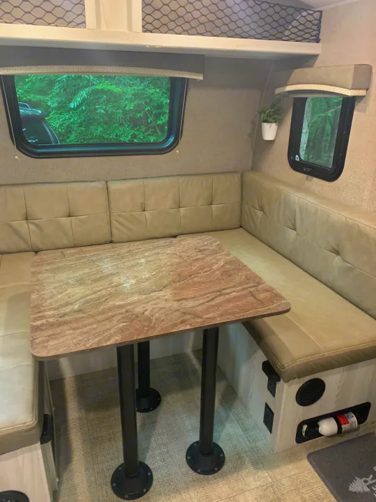 This RV rental's inviting dinette features light-toned bench seating, a marble-style table, and natural window views.. Forest River Rockwood Geo Pro 2020