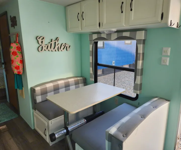 Cozy RV rental dinette with mint walls, white cabinets, and plaid benches, perfect for gathering.. Forest River Palomino Puma 2009