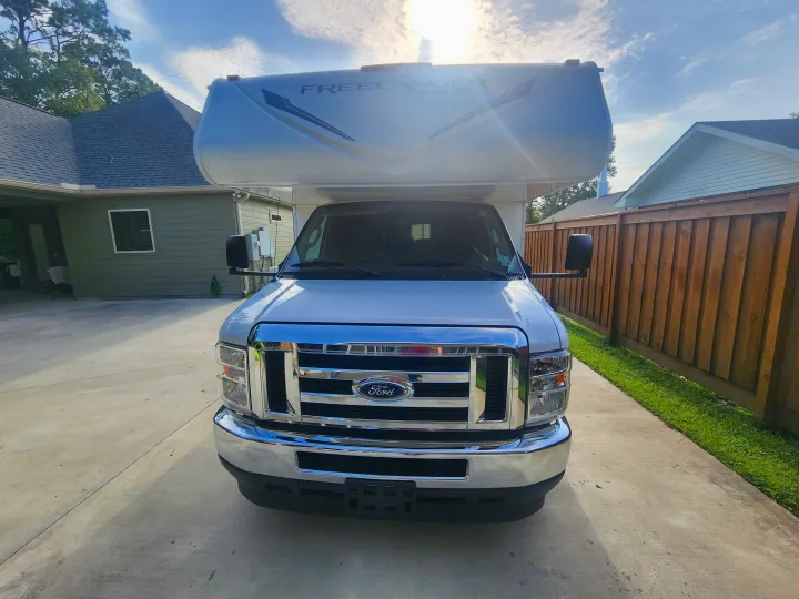 Front view of a white Ford Class C rv rental, a Coachmen Freelander motorhome, parked on a driveway.. Coachmen Freelander 2023