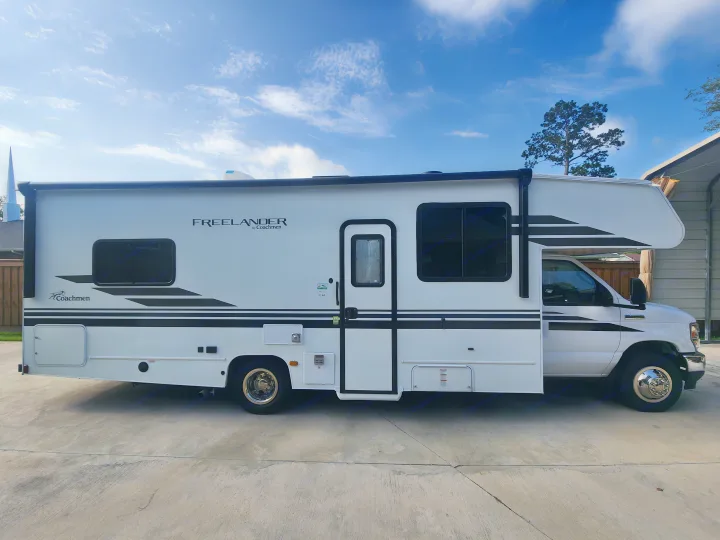White Coachmen Freelander Class C RV, ideal for an rv rental. Features black stripes and side entry.. Coachmen Freelander 2023
