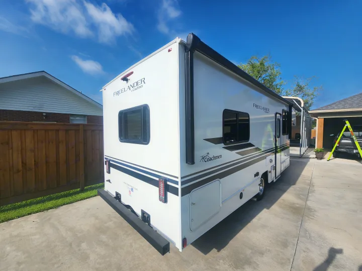 White Coachmen Freelander RV, ideal for your next rv rental adventure. Parked on a driveway under a bright blue sky.. Coachmen Freelander 2023