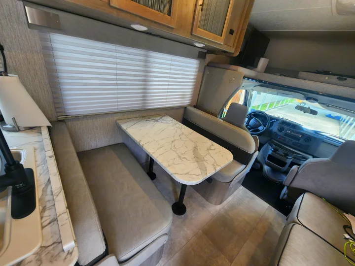 Spacious RV rental interior featuring a modern dinette, plush seating, and the driver's cab.. Coachmen Freelander 2023