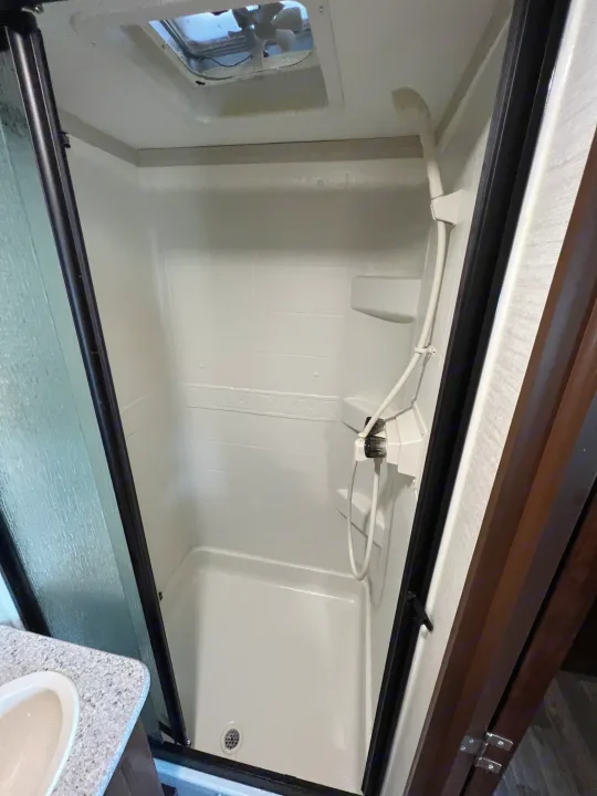 This rv rental features a clean, white shower stall with a convenient shower head, built-in shelf, and ceiling vent.. Keystone RV Bullet Ultra Lite 2016