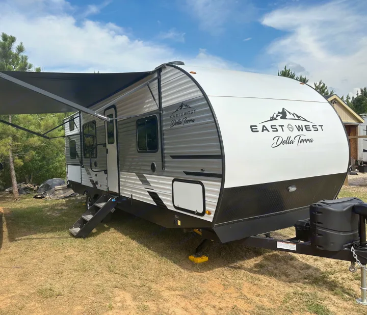 This East West Della Terra travel trailer rv rental, with awning extended, is ready for outdoor adventure.. East to West Della Terra 2023