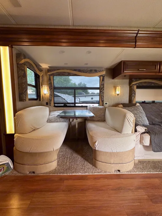 This RV rental features a cozy dinette with plush seating and a table, alongside elegant wood trim, ideal for road trips.. Newmar Canyon Star 2016