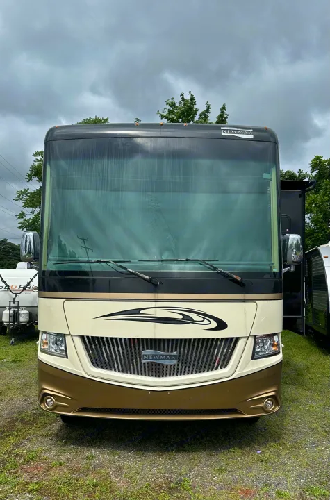 Front view of a cream and gold Newmar RV rental parked outdoors under a cloudy sky, ready for a camping adventure.. Newmar Canyon Star 2016