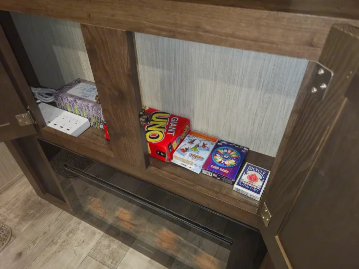 Inside an rv rental, this cabinet neatly stores card games like Uno, a power strip, and tissues, ready for fun and convenience.. Crossroads RV Volante 2019
