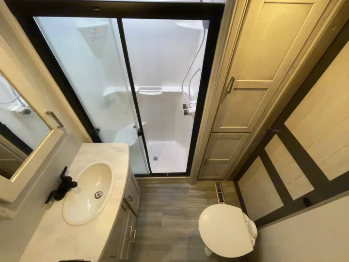 Spacious RV rental bathroom featuring a shower, vanity sink, toilet, and storage cabinets. Perfect for your next adventure.. Keystone Sprinter 2022