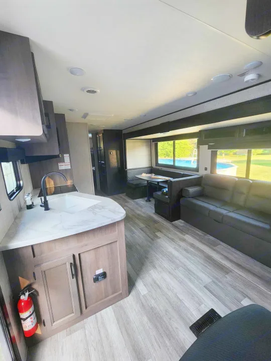 Inside a modern **rv rental**: a bright kitchen, dining booth, comfy sofa, and scenic pool views await your trip.. Jayco Jay Flight 2023
