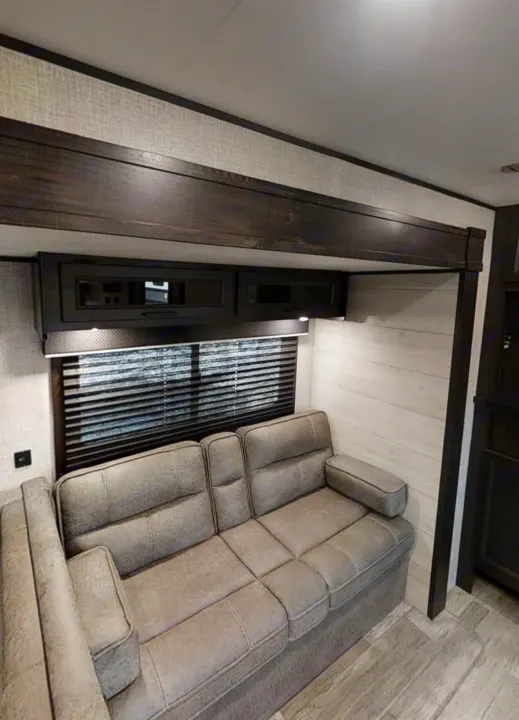 Comfortable RV rental interior featuring a gray sofa, window with blinds, and dark wood cabinetry with lights.. Jayco Jay Flight 2023
