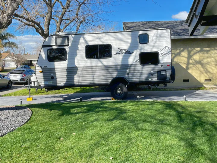 White and grey Jayco Jay Flight Baja travel trailer parked in a sunny driveway, ready for an RV rental adventure.. Jayco Jay Flight SLX 2022