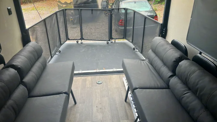 RV rental: Spacious toy hauler interior with black sofas converting to beds, facing a mesh rear patio. Great for adventures!. Coachmen Catalina 2021