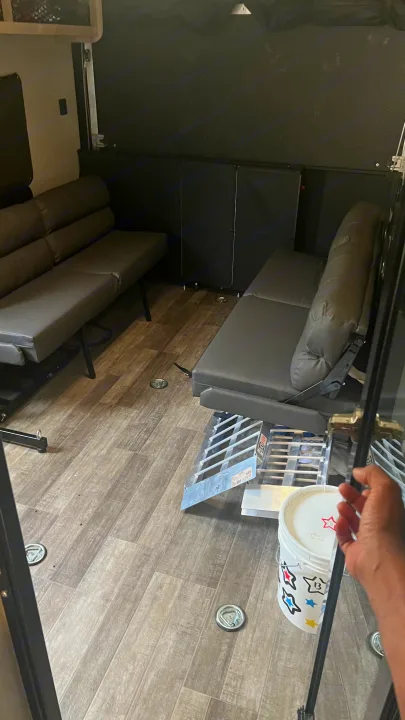 RV rental: Toy hauler interior with two gray convertible sofas, wood-look floor, tie-downs, and storage.. Coachmen Catalina 2021
