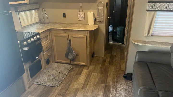 Explore this rv rental's functional interior: a compact kitchen with stove, sink, and cabinets, plus a cozy living space and hallway.. Coachmen Catalina 2021