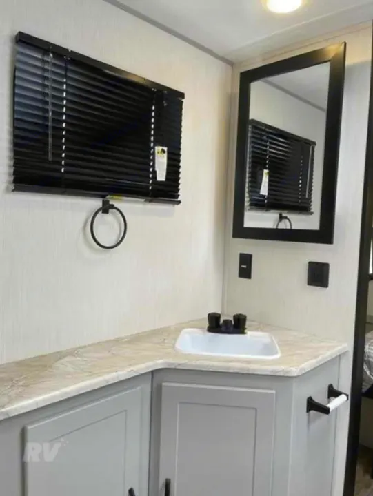 RV rental: Modern bathroom featuring a vanity with sink, black mirror, and blinds. Clean, functional space with grey cabinets.. Forest River Vibe 2022