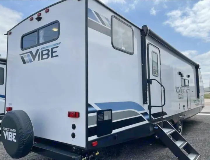 Explore with this white Forest River VIBE travel trailer, ideal for rv rental trips. It has blue/grey accents & entry steps.. Forest River Vibe 2022