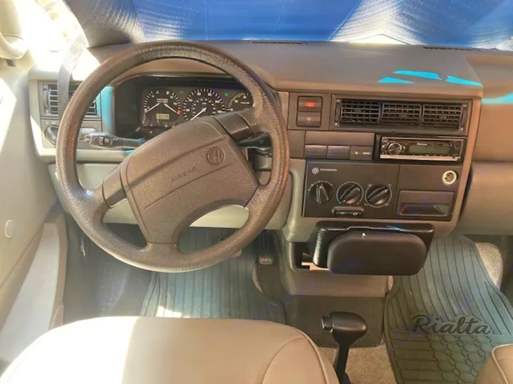 Driver's view inside a VW Rialta RV rental: Grey interior, showing the dashboard, steering wheel, gauges, and climate controls.. Winnebago Rialta 1998