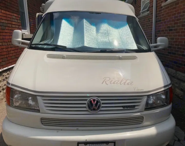 Front view of a white Volkswagen Rialta Classic RV rental, featuring a sunshade in the windshield.. Winnebago Rialta 1998