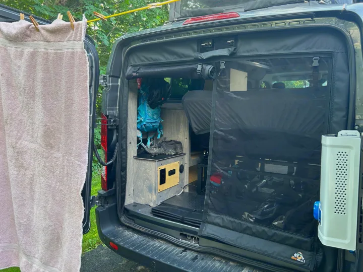 RV rental camper van setup: Back doors open revealing custom interior, bug screen, and clothesline. Ideal for van life.. Ford Custom Transit 2022
