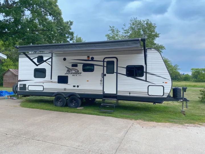A white Jayco travel trailer, an excellent RV rental, parked with its awning extended for a comfortable outdoor stay.. Jayco Jay Flight SLX 2017