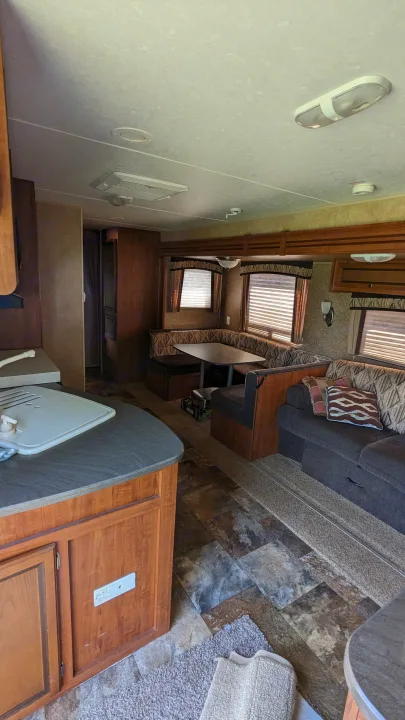 RV rental interior with kitchen, booth dinette, and sofa lounge. Features wood cabinets, patterned upholstery, and mixed flooring.. Jayco Jay Flight 2012