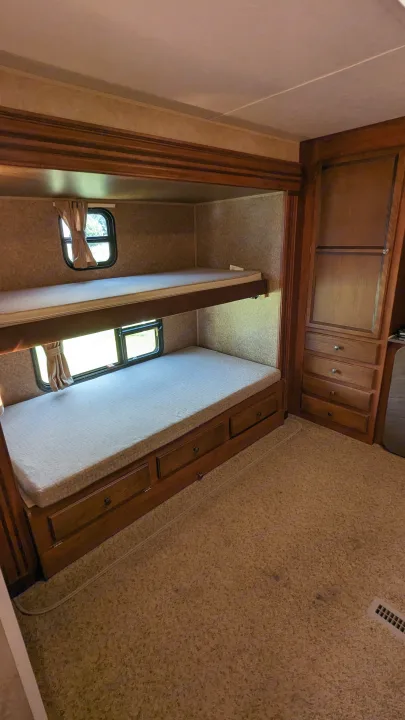 Cozy RV rental bunk beds with windows, curtains, built-in storage, and carpeted flooring, ready for travel.. Jayco Jay Flight 2012