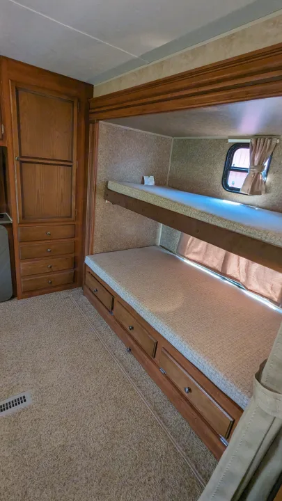 This RV rental features a cozy bunk bed area with integrated wooden storage and a carpeted floor.. Jayco Jay Flight 2012