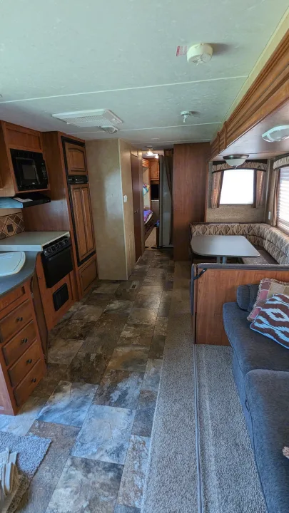 RV rental interior: kitchen with stove, microwave, fridge; dining booth, sofa, and hallway to bedroom area.. Jayco Jay Flight 2012