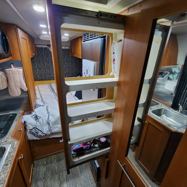 Spacious rv rental interior showcasing a compact kitchen, comfortable bed area, and smart overhead storage solutions.. Roadtrek Roadtrek Class B 2017