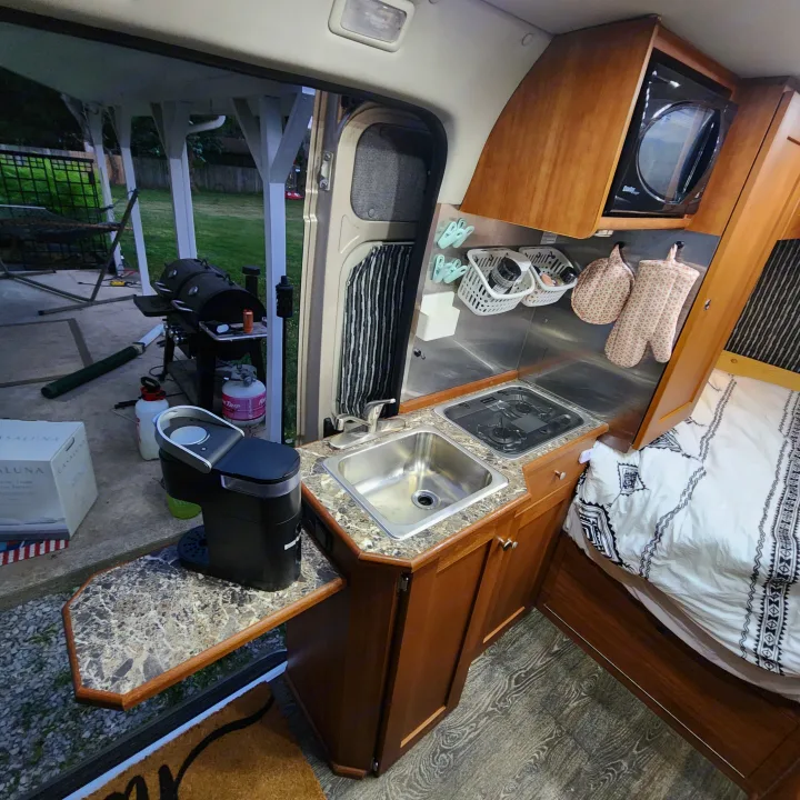 Cozy RV rental interior with a well-equipped kitchen, comfortable bed, and outdoor grill area for enjoyable trips.. Roadtrek Roadtrek Class B 2017