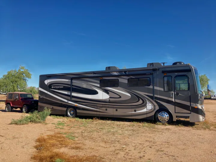 Spacious gray Fleetwood Expedition RV with a red Jeep in a desert setting, ready for your next rv rental adventure!. Fleetwood Expedition 38B 2011