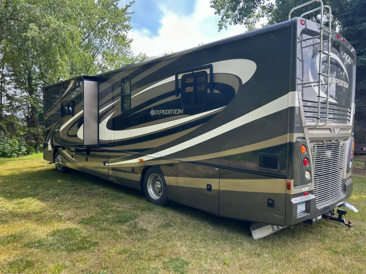 Expedition RV, a stylish dark and light motorhome, great for an rv rental, parked on grass with trees. Slide-out extended.. Fleetwood Expedition 38B 2011
