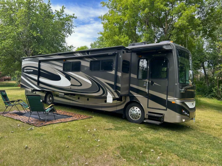Spacious motorhome for an ideal RV rental camping trip, featuring outdoor seating at a scenic campsite.. Fleetwood Expedition 38B 2011