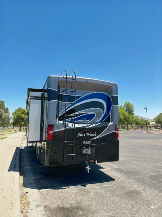 Rear view of a large Four Winds RV rental with its slide-out extended, parked in a bright, sunny outdoor lot.. Thor Four Winds 2017