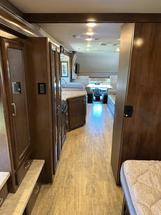 An RV rental interior hallway showing the kitchen, living area, and cockpit. A rear bedroom mattress is visible on the right.. Thor Four Winds 2017