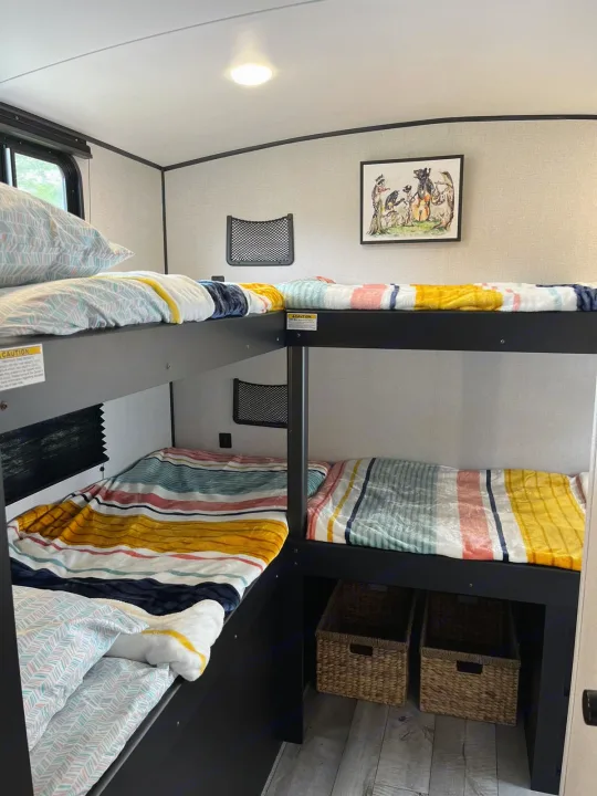 Inside an RV rental: vibrant bunk beds with striped bedding offer cozy sleeping for the whole family during travel.. Keystone RV Springdale 2022