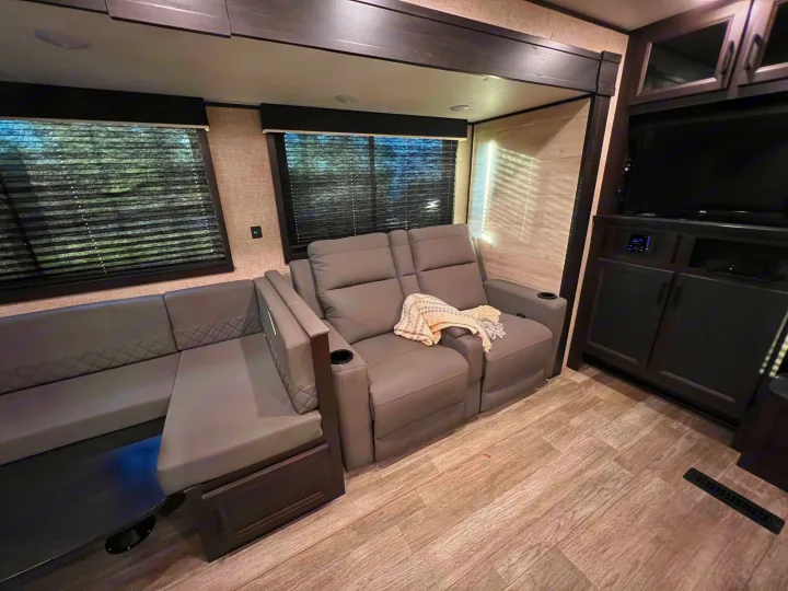Spacious RV rental interior featuring a gray L-shaped dinette, comfy recliners, and TV entertainment system.. Jayco Jay Flight 2023