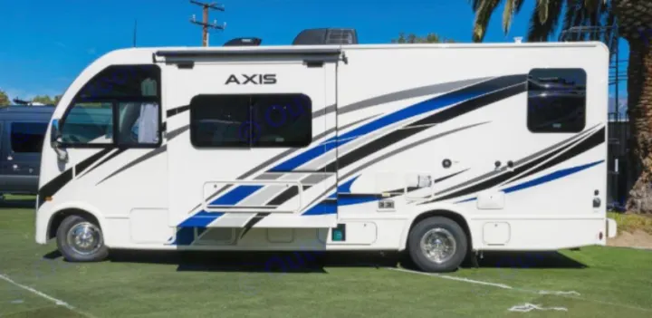 A white Thor Axis motorhome, available for rv rental, featuring blue/black graphics, sits on green turf.. Thor Axis 2023