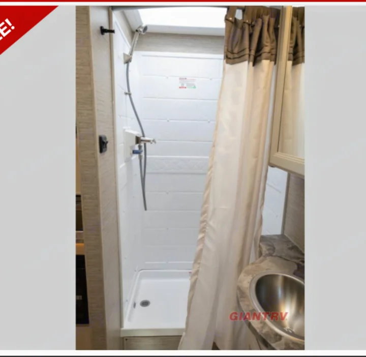 RV rental: Compact bathroom with white shower stall, handheld shower, and small sink with countertop. Perfect for trips!. Thor Axis 2023